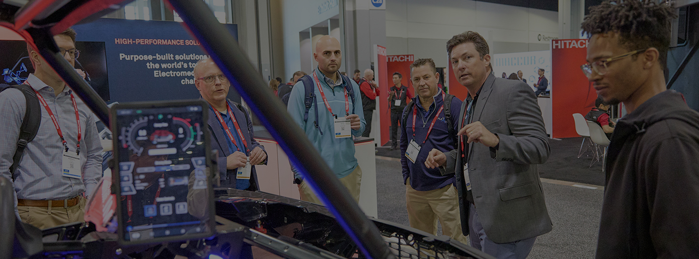 Several individuals inspecting a vehicle at an event, showing interest and interacting with each other