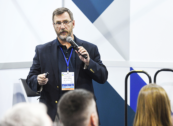 A conference speaker presenting in front of the audience and holding a microphone