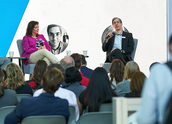 A man and a woman presenting seating down and presenting in front of audience